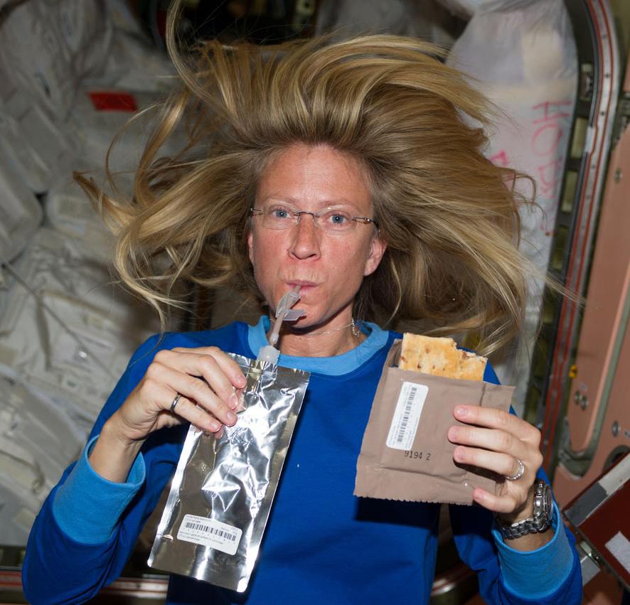 Astronaut Karen Nyberg,Expedition 36 flight engineer,is photographed with food and drink packets while in the Node 1 module.