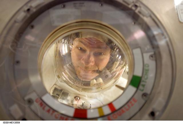 NASA astronaut Michael Lopez-Alegria peeks through an airlock window.