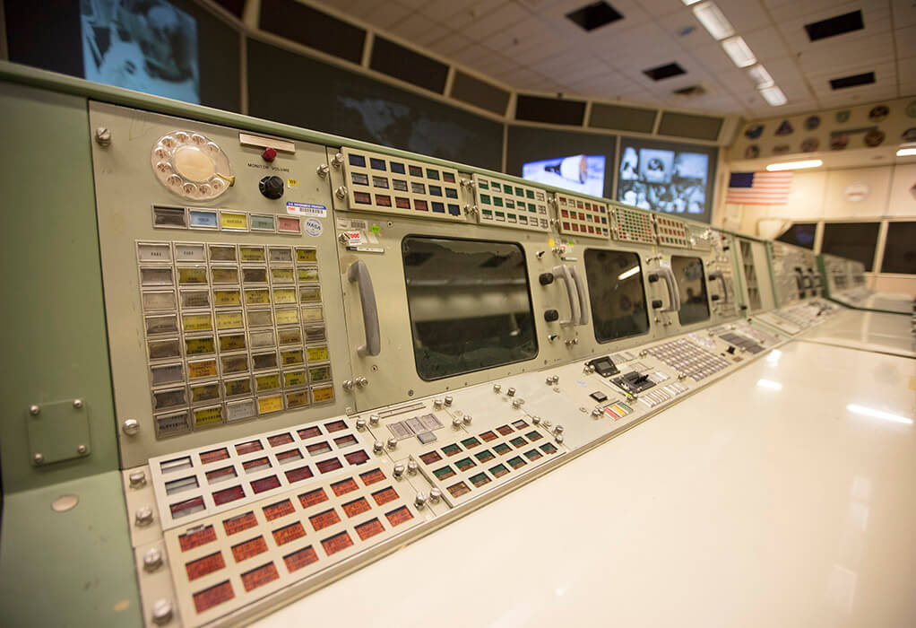 A view of a worn-down console in Historic Mission Control. After decades of use, the buttons have gone missing or have become faded, the paint has become chipped and scratched and the monitor has become discolored.