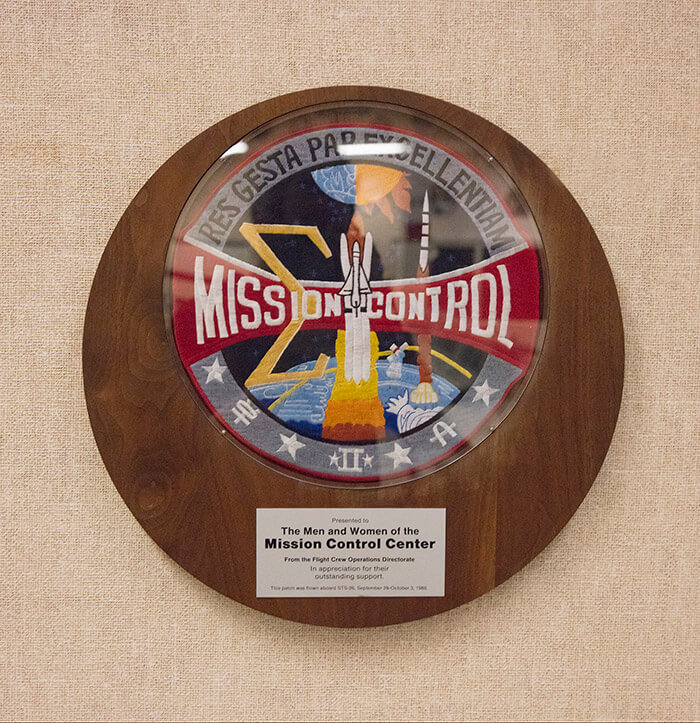 A flown mission patch presented to the workers of Mission Control is featured in Historic Mission Control.