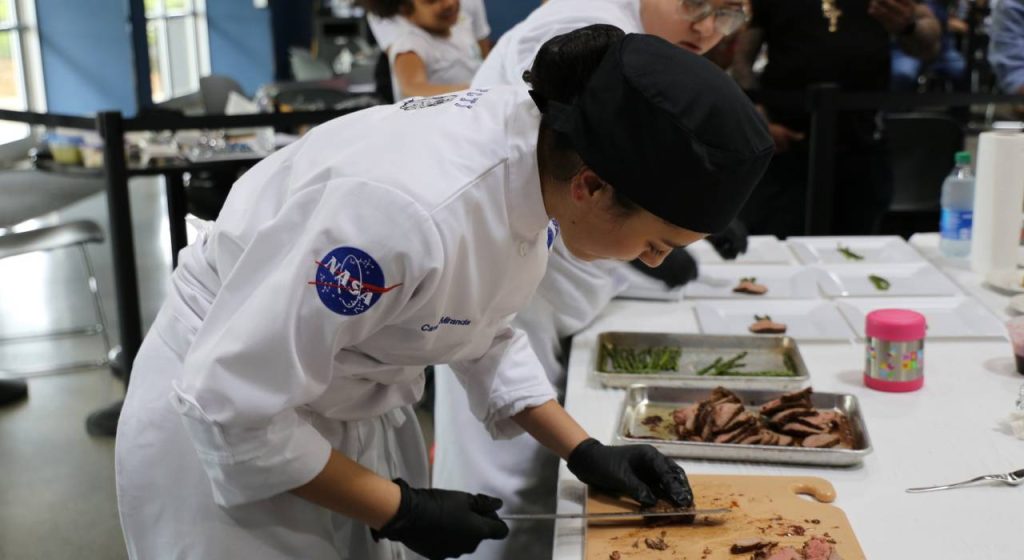 HUNCH Culinary Challenge participant prepares an “Out of this World” dish comprised of a 6 oz filet mignon and sides at Space Center Houston’s Food Lab in April 2022.  