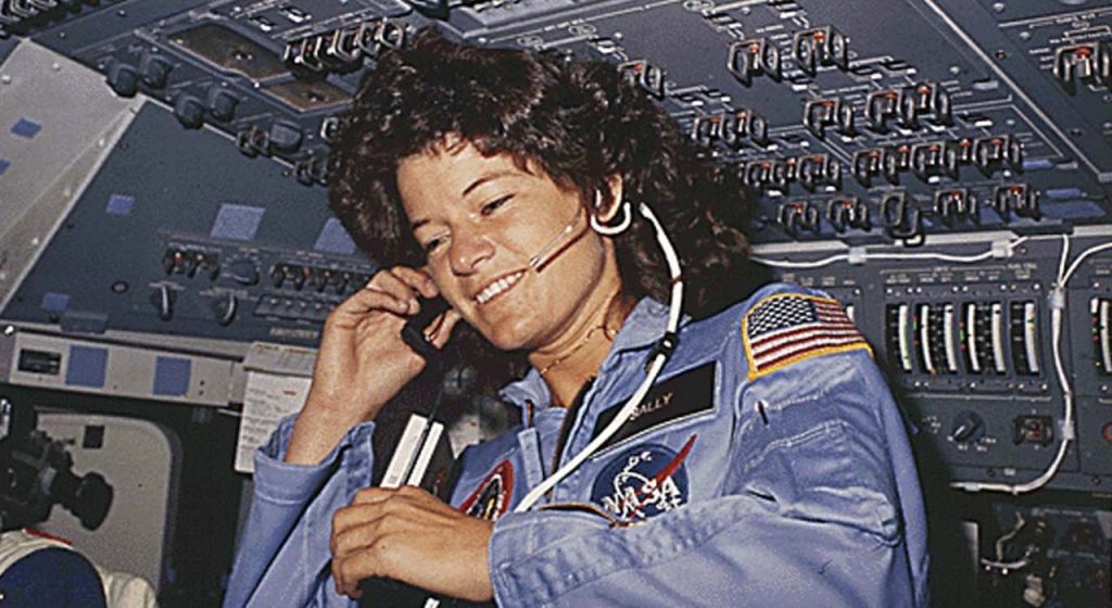 Sally Ride, the first American female astronaut, wearing a headset in the cockpit of a shuttle.
